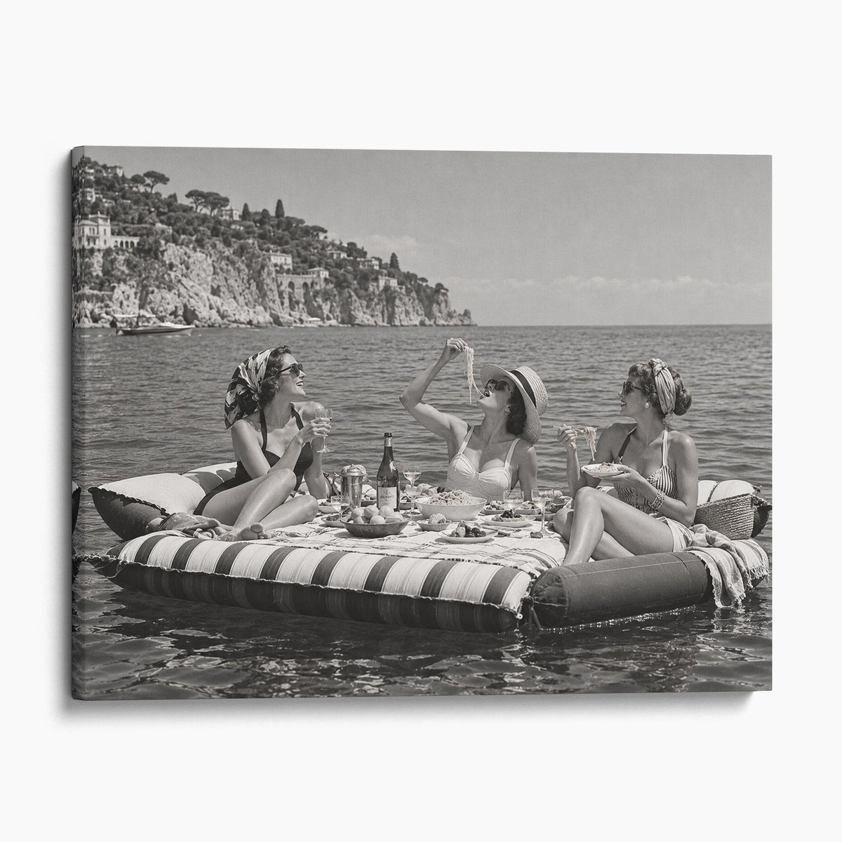 Floating Luncheon, three young women eat spaghetti on inflatable mattresses